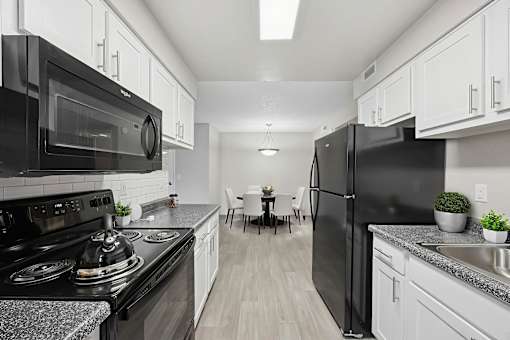 A modern kitchen with black appliances and white cabinets.