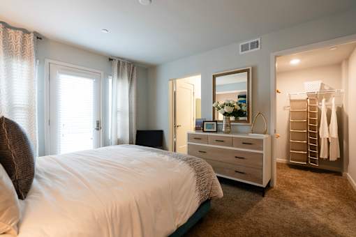 A bedroom with a large bed, a dresser, and a mirror.