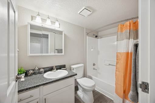 A bathroom with a white toilet, sink, and mirror.