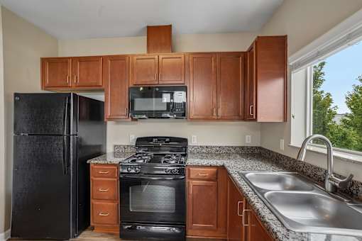 A kitchen with black appliances and wooden cabinets.