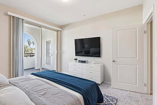 A bedroom with a bed, dresser, and television.