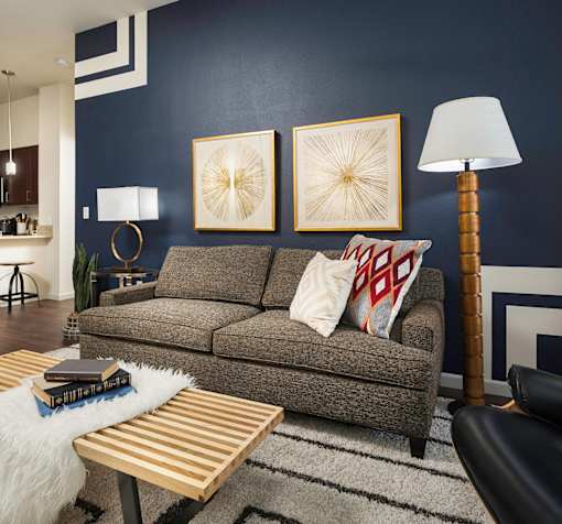 A living room with a grey couch, a wooden coffee table, and a lamp.