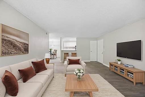 A living room with a white couch, a wooden coffee table, and a painting on the wall.