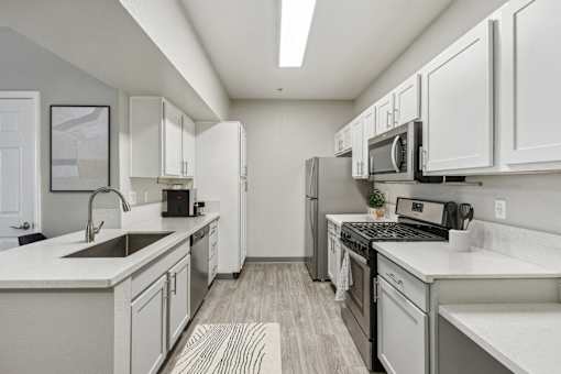 a spacious kitchen with white cabinets and stainless steel appliances