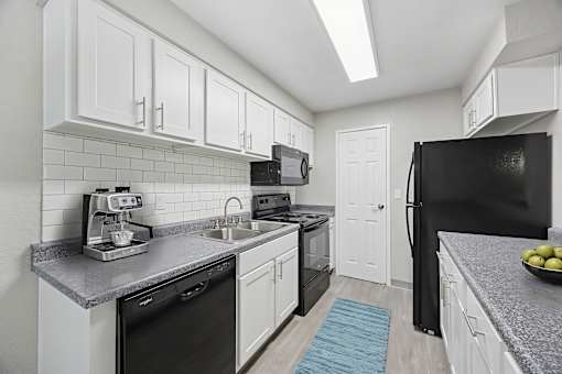 A kitchen with black appliances and white cabinets.