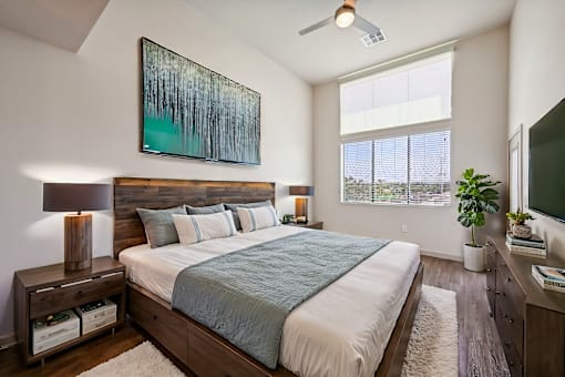 A bedroom with a large bed and a painting above it.