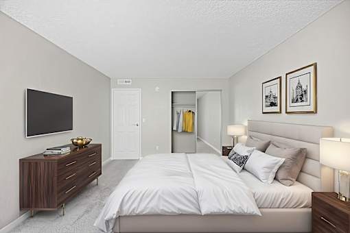 A bedroom with a large bed and a TV on the wall.