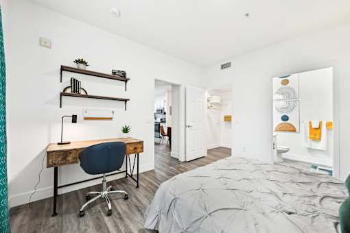 A bedroom with a bed, desk, and chair.