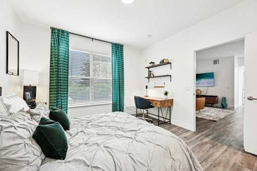 A bedroom with a large bed and a desk with a chair.