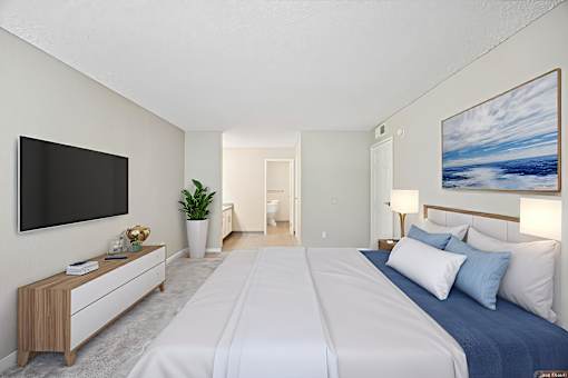 A bedroom with a large bed and a flat screen TV mounted on the wall.