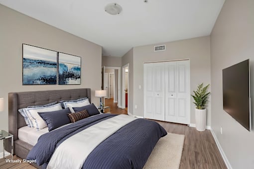 A bedroom with a large bed and a painting on the wall.