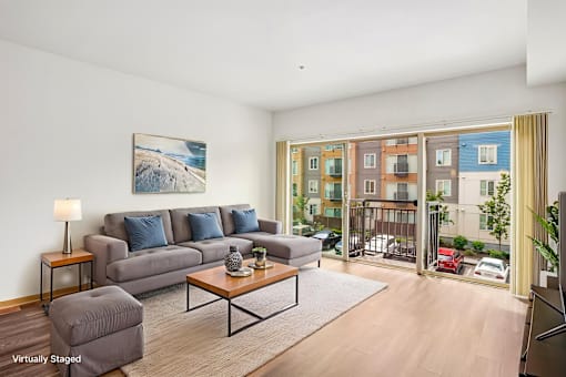 A living room with a grey couch and a painting on the wall.
