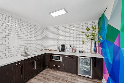 A kitchen with wooden cabinets and a white tiled wall.