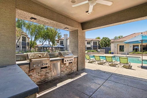A patio with a pool and a grill.