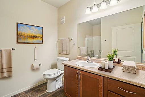 A bathroom with a toilet, sink, and a painting on the wall.