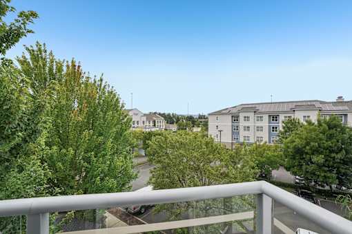 A balcony overlooks a residential area with houses and trees.