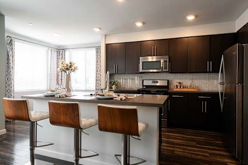 A modern kitchen with dark brown cabinets and a white island.