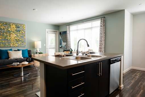 A modern kitchen with a black countertop and stainless steel appliances.