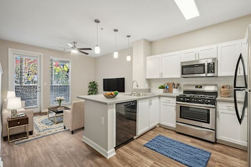 A kitchen with white cabinets and a blue rug on the floor.