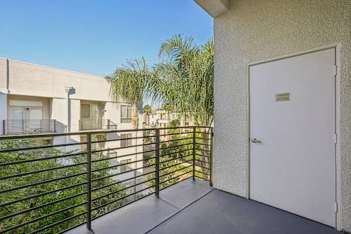 A balcony with a white door and a black railing.