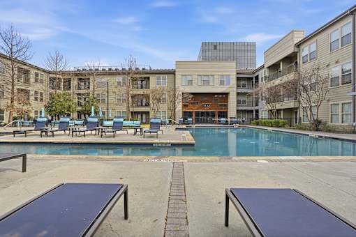 A swimming pool surrounded by a building and a bench.