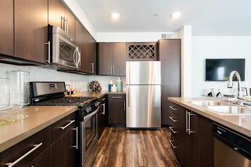 A modern kitchen with dark wood cabinets and stainless steel appliances.