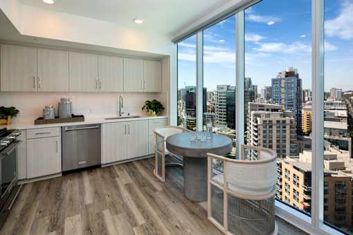 A modern kitchen with a table and chairs and a view of the city.