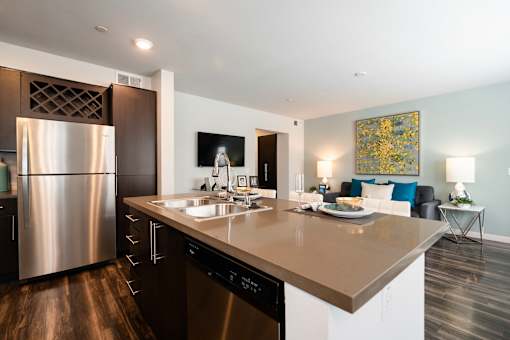 A modern kitchen with a stainless steel refrigerator and a wooden floor.