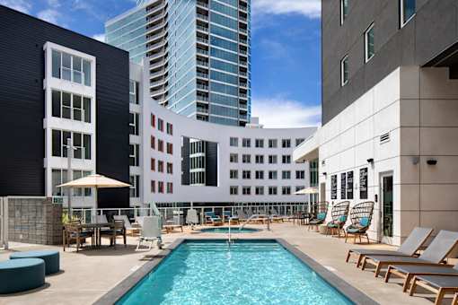 A pool area with chairs and a building in the background.
