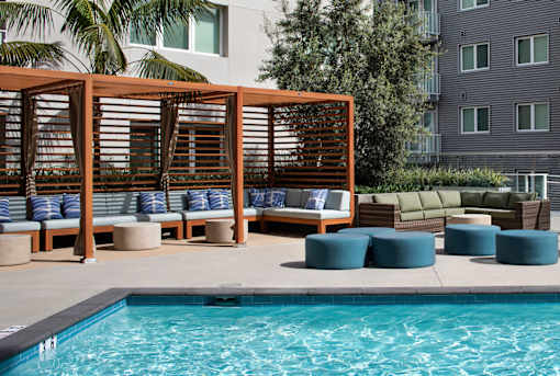 A pool area with a wooden structure and cushions.