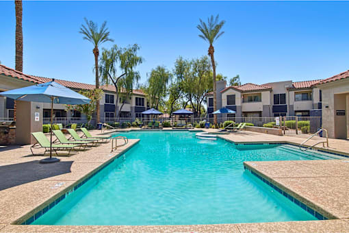 A large swimming pool surrounded by sun loungers and umbrellas.