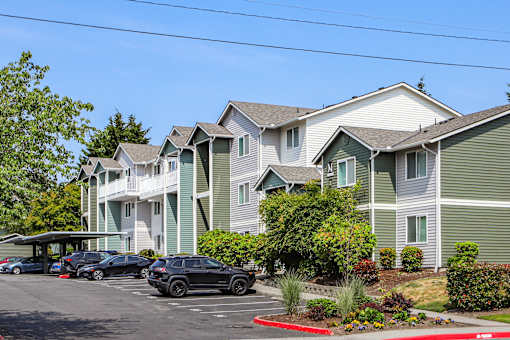 A row of houses with cars parked in front.