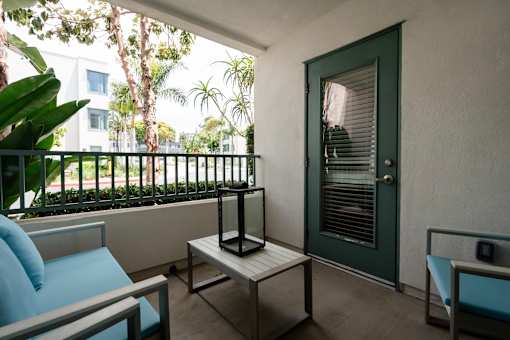 A balcony with a table and chairs and a door.