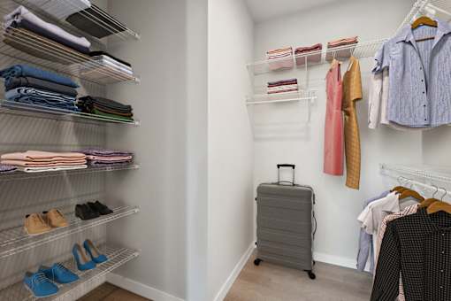 a walk in closet with shelves and a suitcase