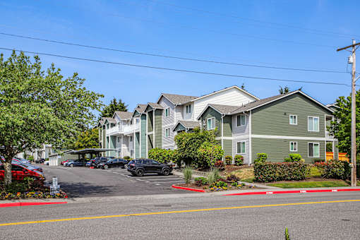 A row of houses with cars parked in front.