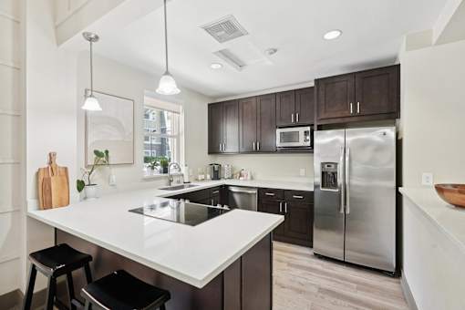 A modern kitchen with a white countertop and stainless steel appliances.