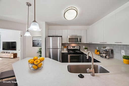 A modern kitchen with a stainless steel refrigerator and a bowl of lemons on the counter.