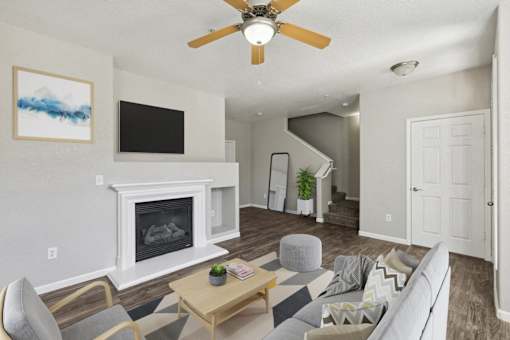 an open living room with a fireplace and a ceiling fan