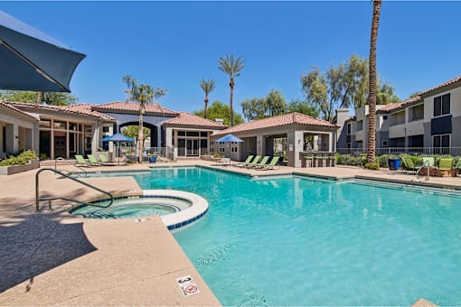 A swimming pool surrounded by palm trees and lounge chairs.