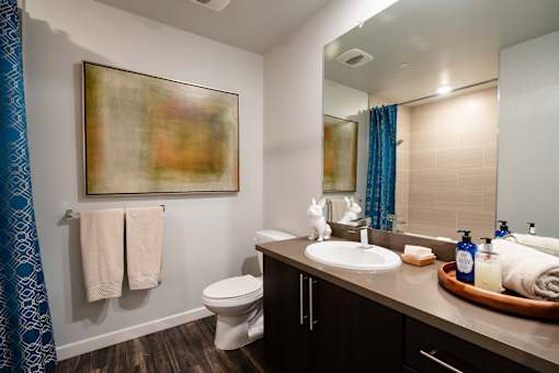 A bathroom with a toilet, sink, and a painting on the wall.