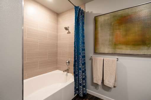 A bathroom with a white tub and blue shower curtain.