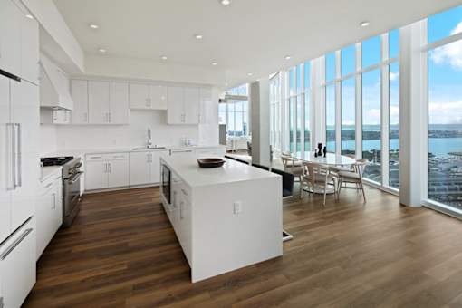 A modern kitchen with white appliances and wooden floors.