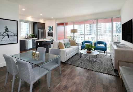 A modern living room with a glass table and grey chairs.