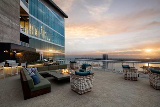 A rooftop patio with a couch, chairs, and a table with a lit candle.