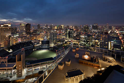 A rooftop bar overlooks a city skyline at night.
