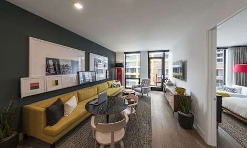 a living room with a yellow couch and a black wall and a balcony