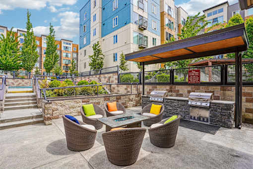 A patio with a table and chairs and a grill.