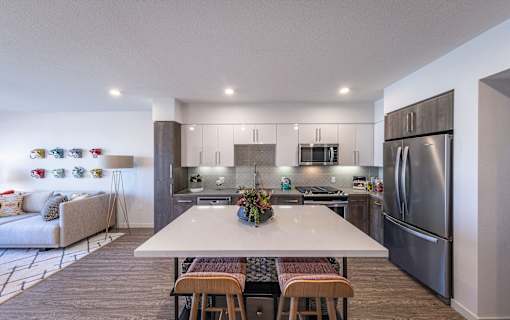 a kitchen with stainless steel appliances and a white island with four chairs