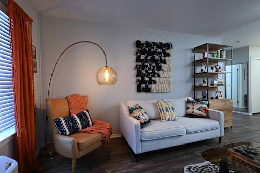 A living room with a white couch and a chair with orange cushions.