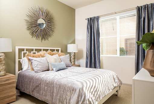 A bedroom with a bed, a mirror, and two lamps.